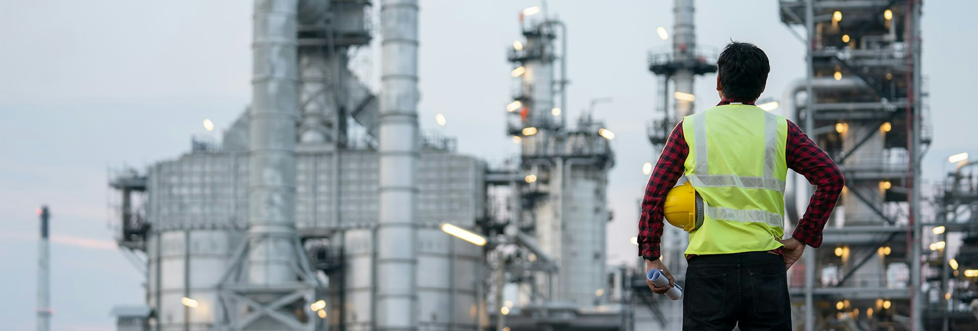 Man standing in front of oil refinery