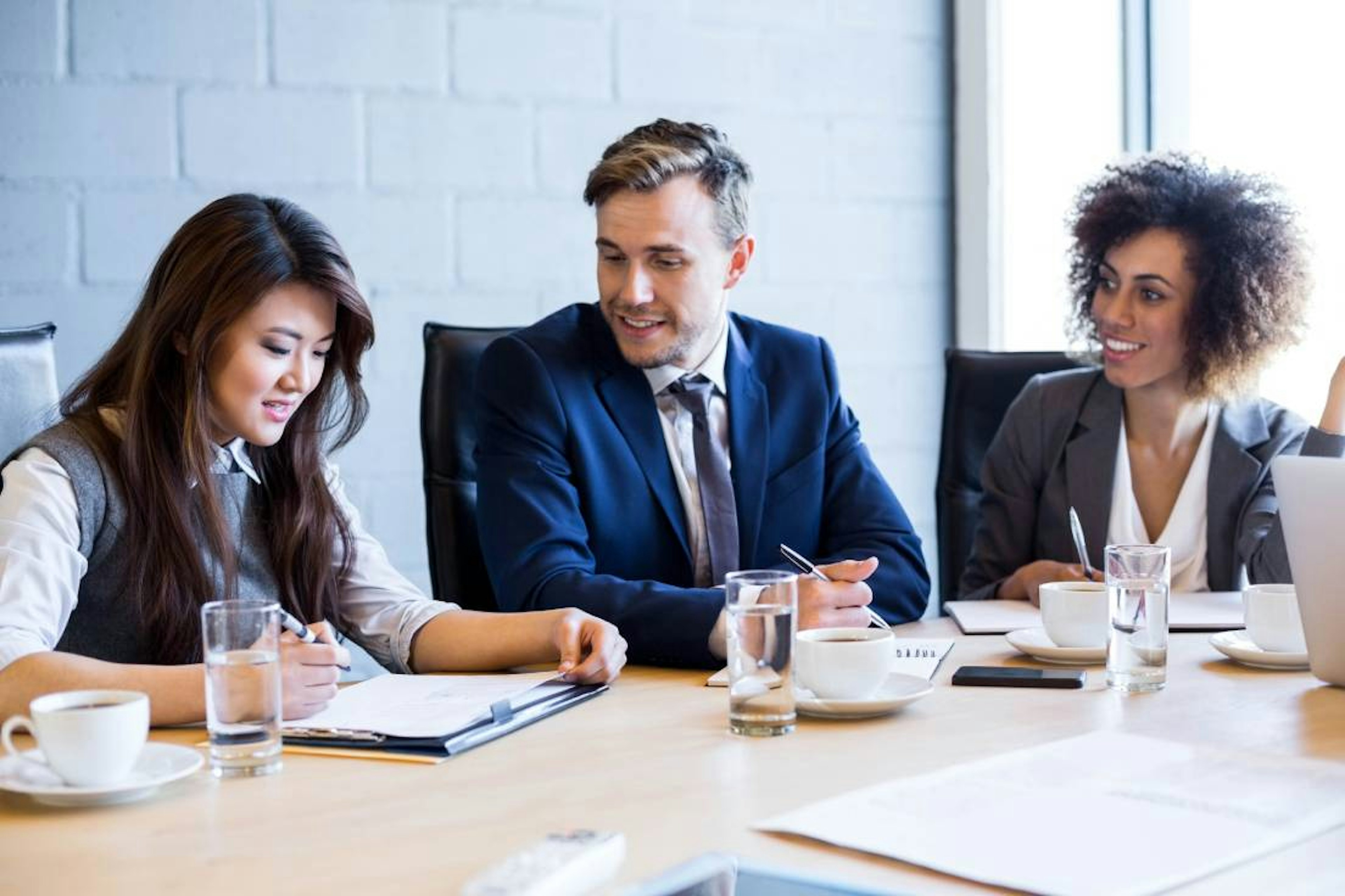 Frauen und ein Mann am Schreibtisch in einem Meeting