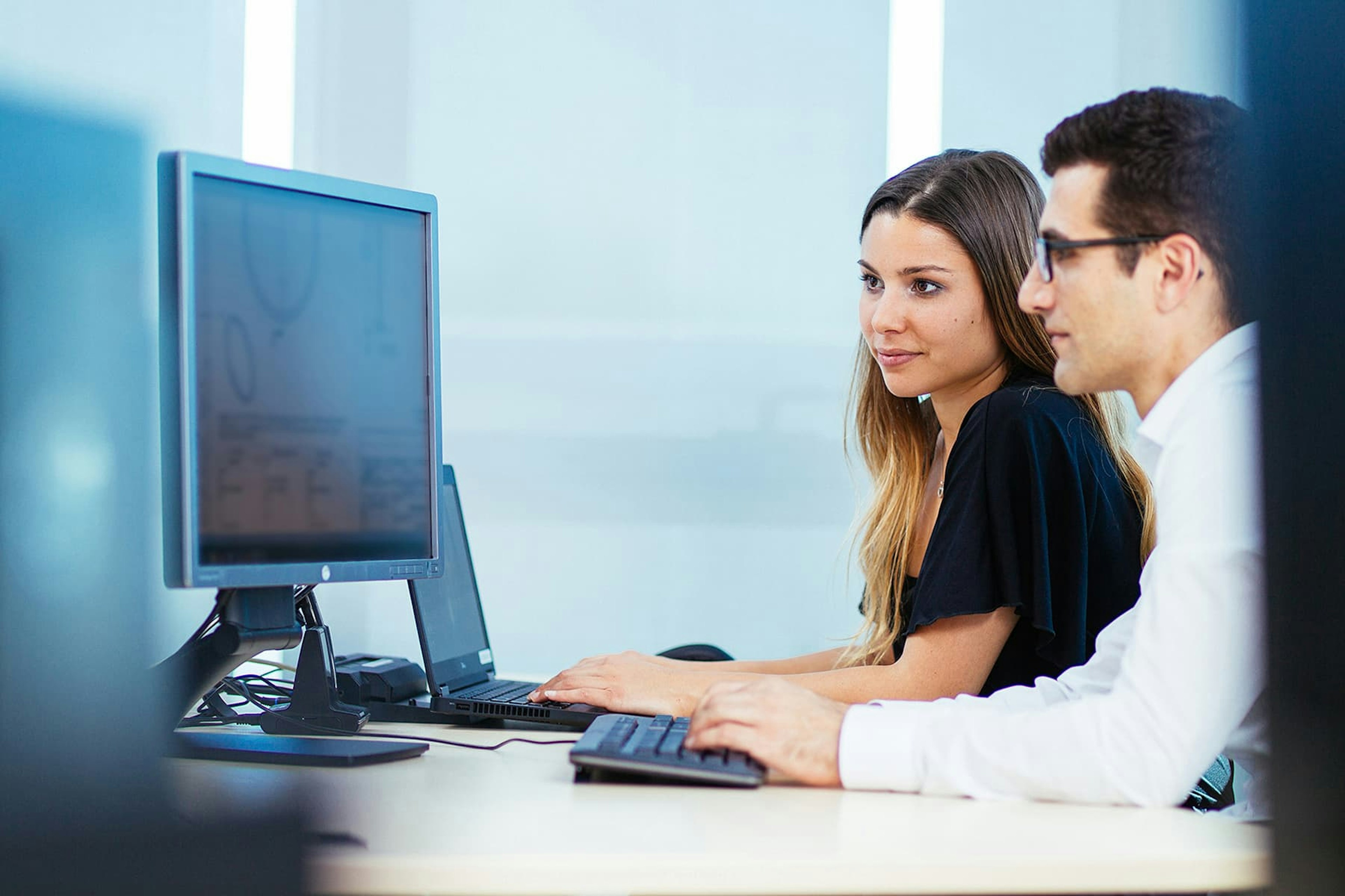 Man and woman at a desk looking at a computer screen
