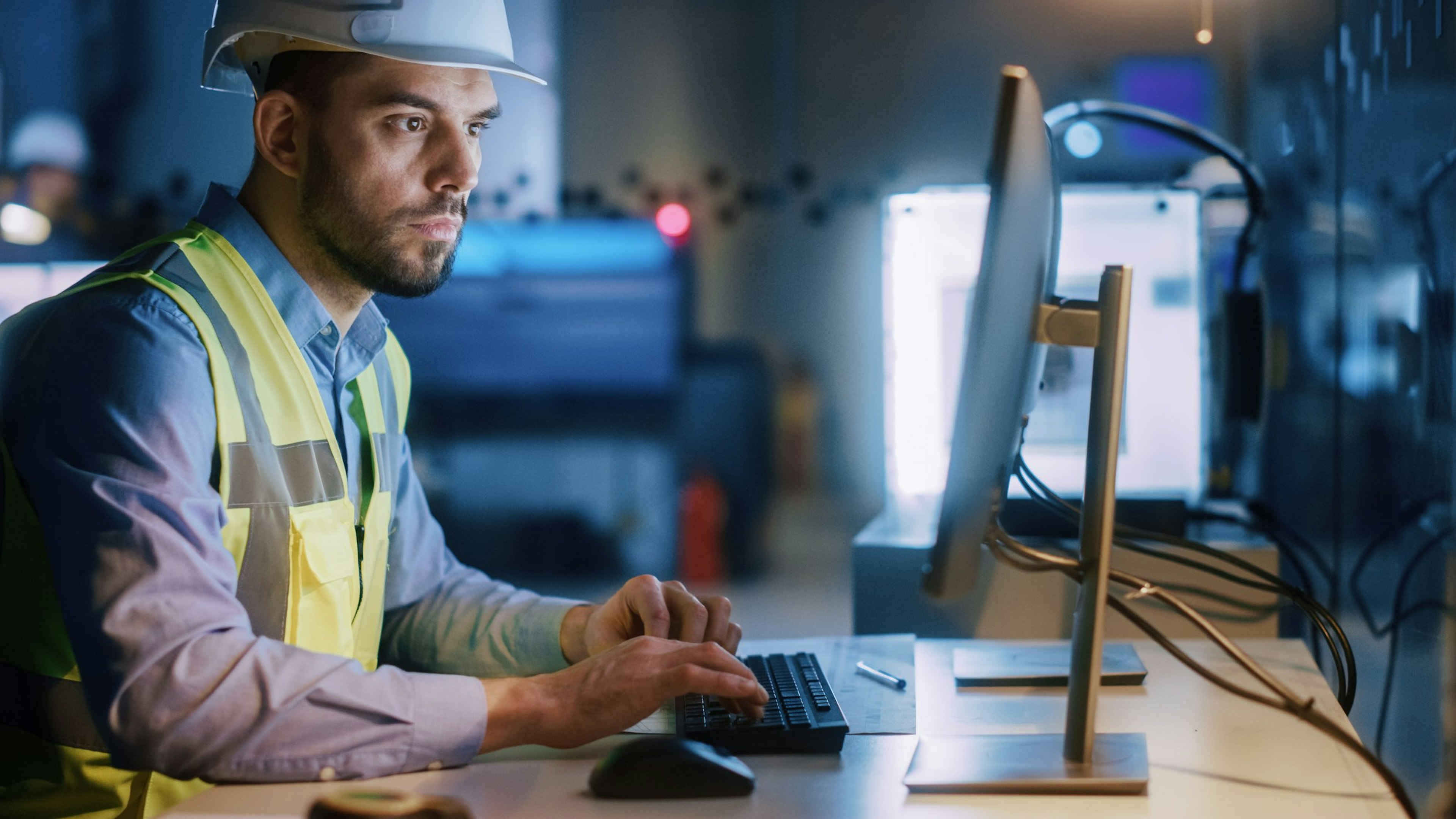 St process engineer in an oil and gas role looking at a screen while wearing PPE