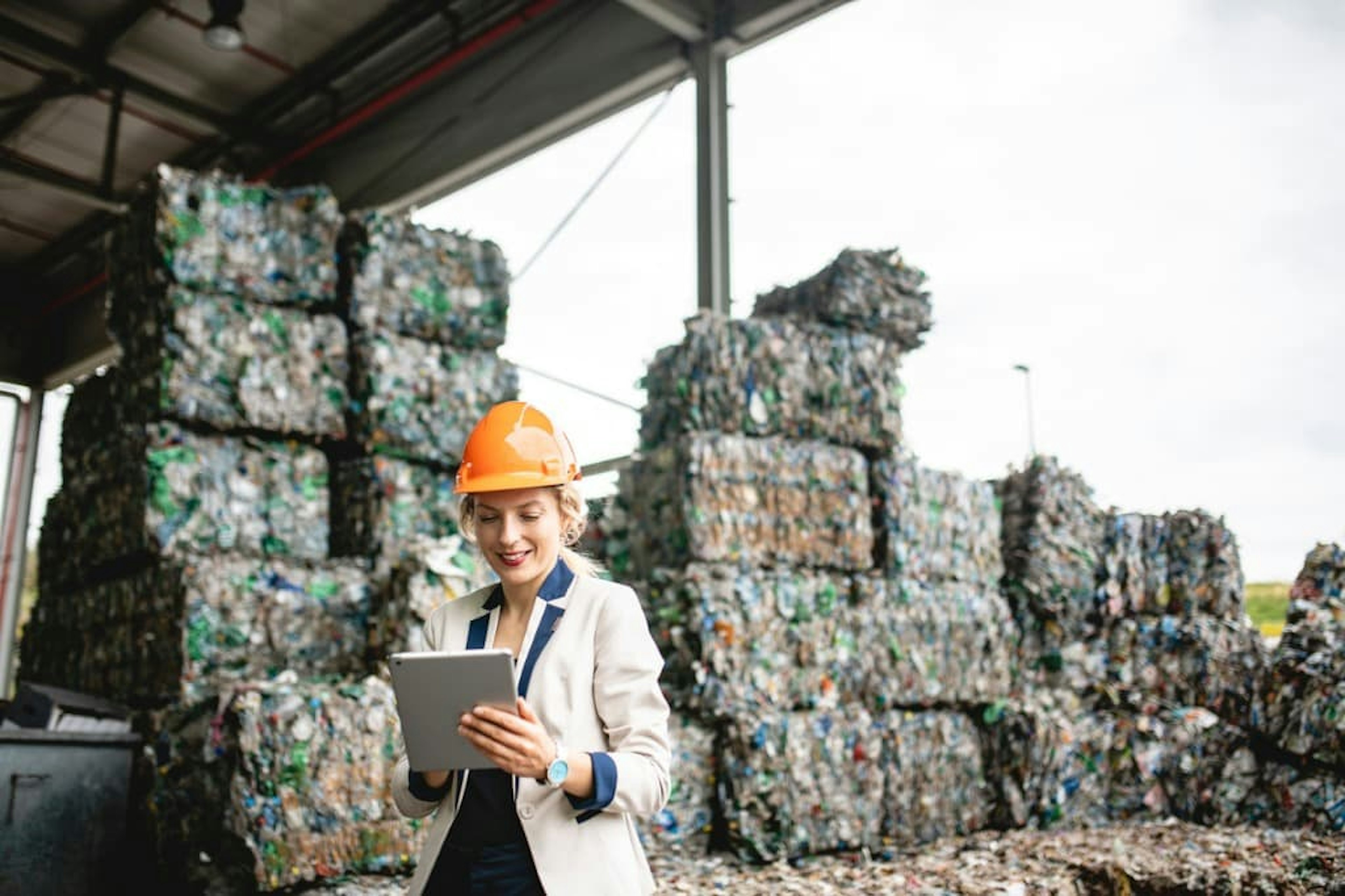 Mitarbeiterin mit orangenem Helm in der Abfallwirtschaft